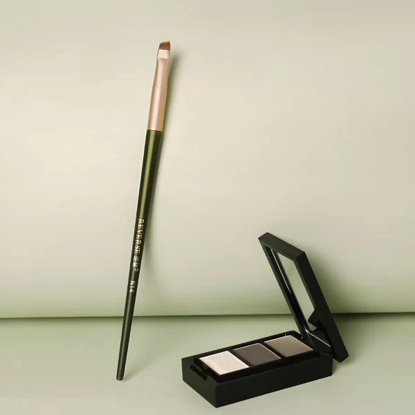 Eyeliner brush with green handle displayed next to brow powder palette.